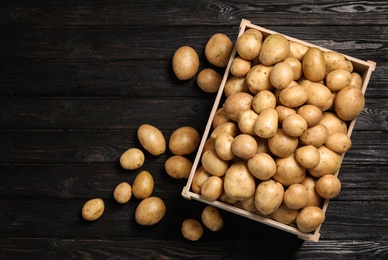 Raw fresh organic potatoes on black wooden background, top view