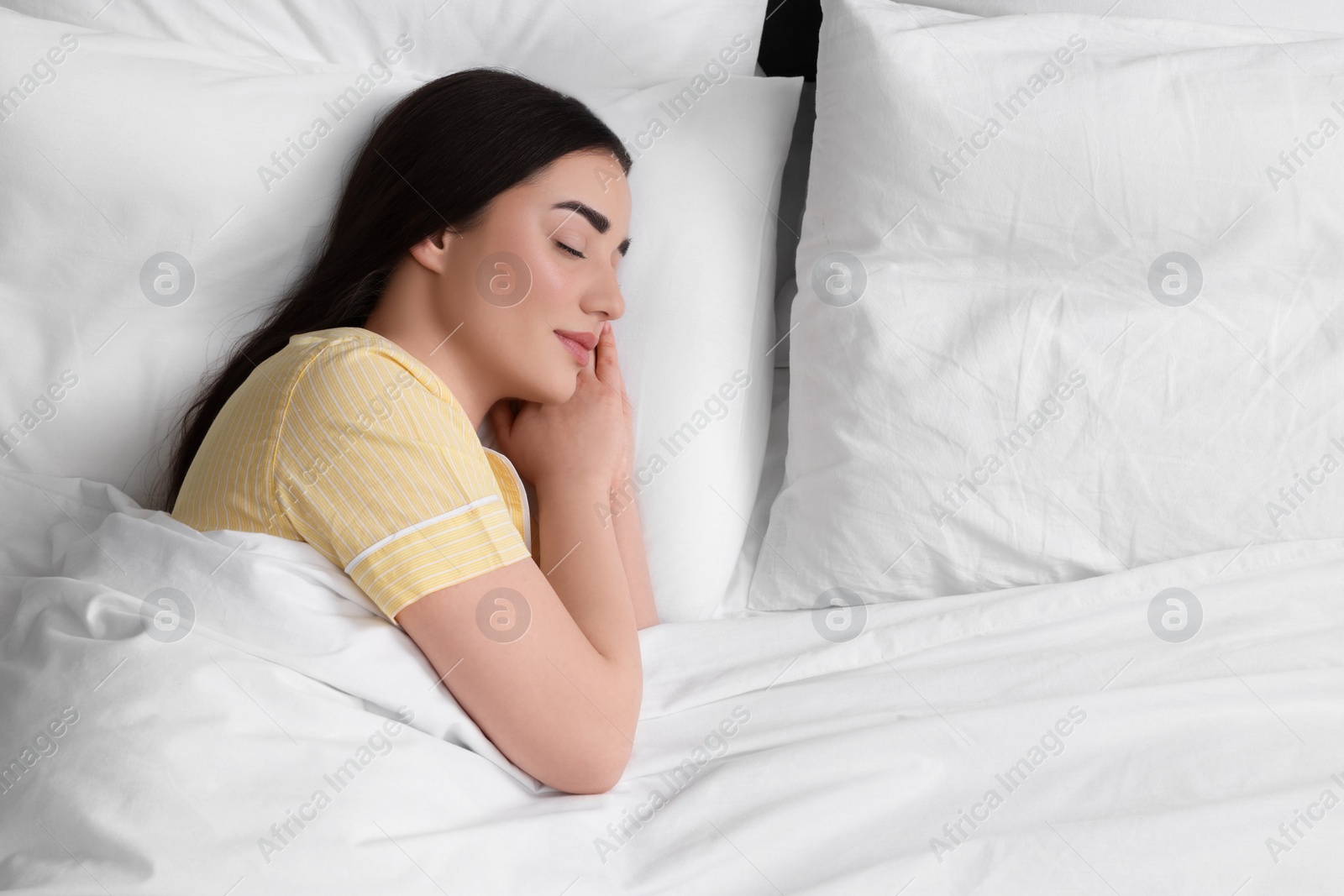 Photo of Beautiful young woman sleeping in soft bed, above view