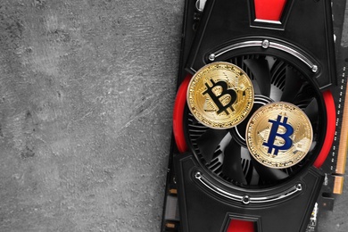 Bitcoins and video card on grey background, space for text