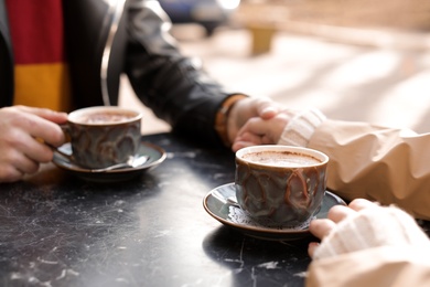 Photo of Couple enjoying tasty aromatic coffee at table, closeup view