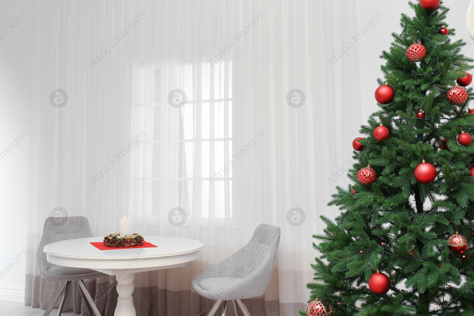 Photo of Stylish Christmas interior with fir tree, table and chairs