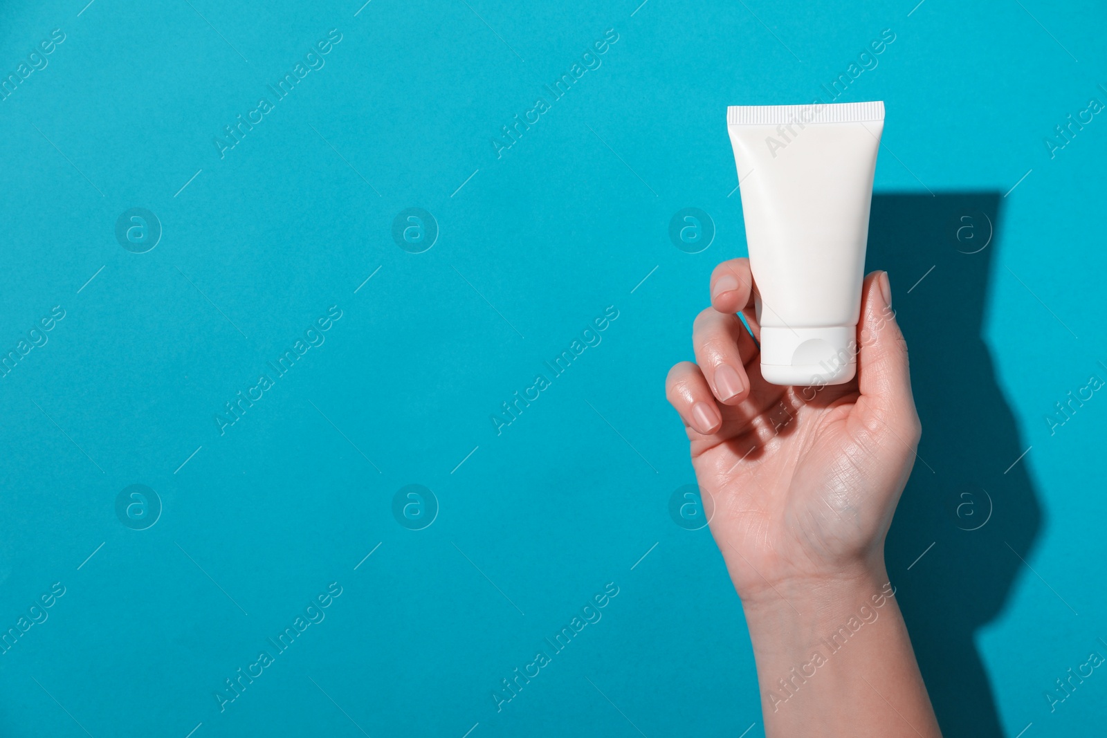 Photo of Woman with tube of hand cream on light blue background, top view. Space for text