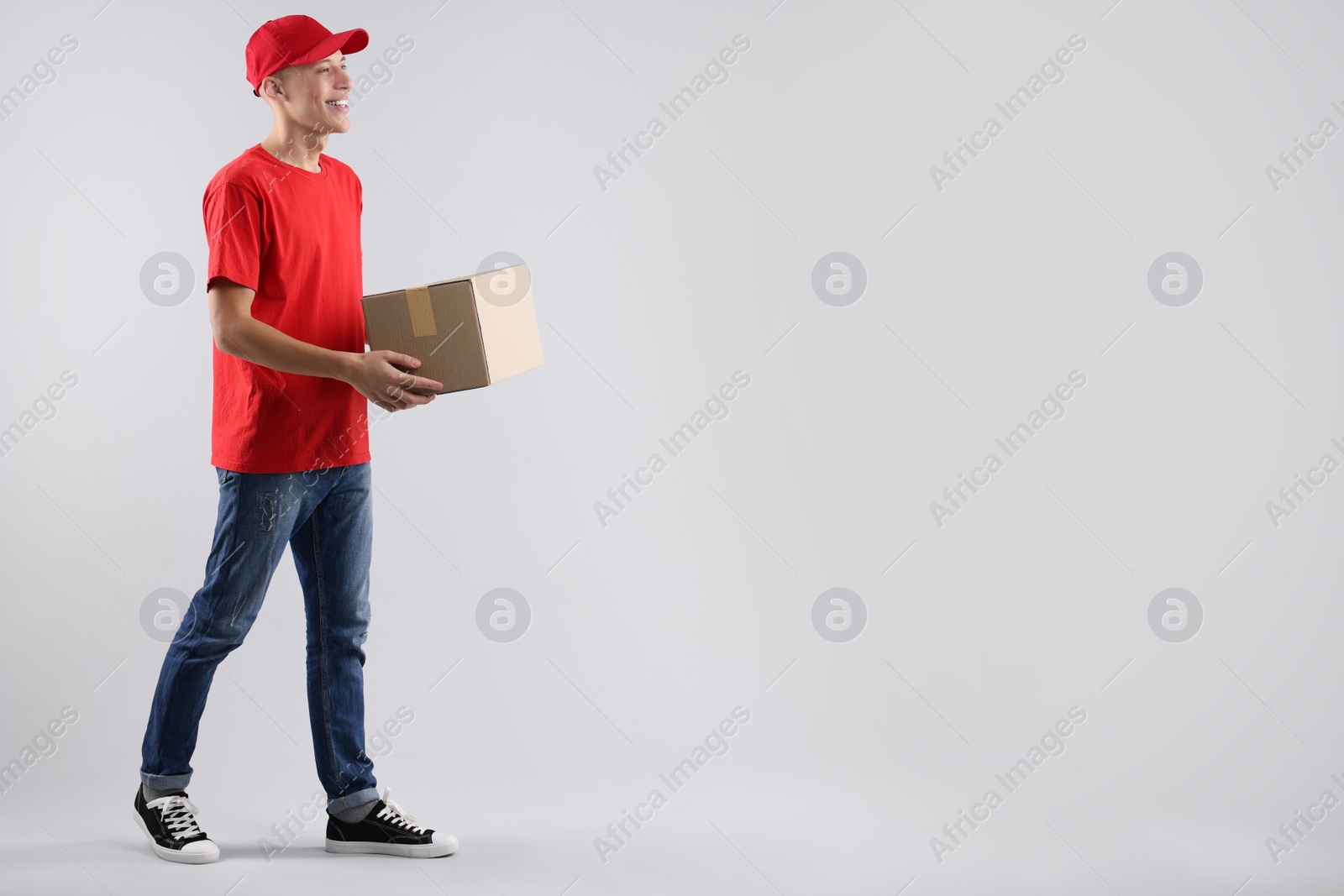 Photo of Happy courier with parcel on light grey background. Space for text