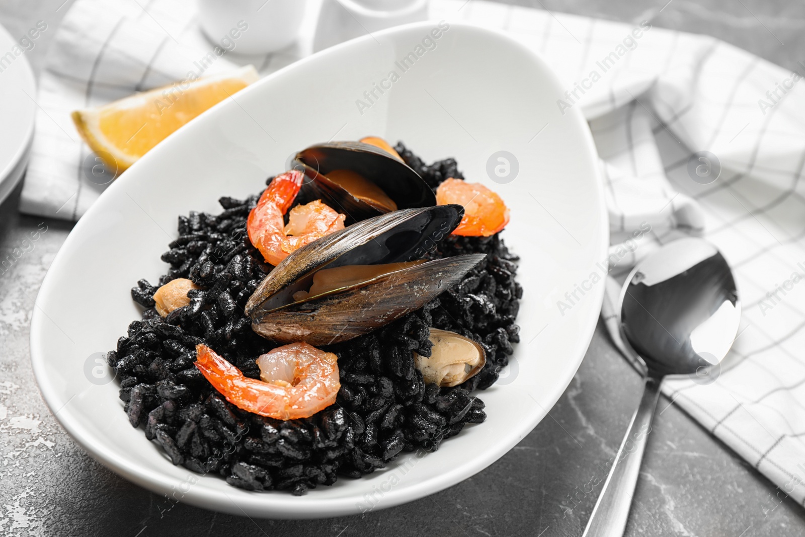 Photo of Delicious black risotto with seafood on marble table