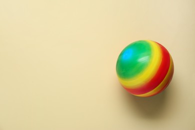 Photo of Bright rubber kids' ball on beige background, top view. Space for text