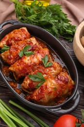 Photo of Delicious stuffed cabbage rolls cooked with tomato sauce on wooden table