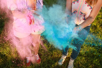 Photo of Women with colorful powder dyes outdoors, closeup. Holi festival celebration
