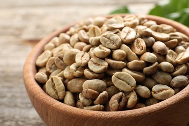 Photo of Green coffee beans in wooden bowl on table, closeup