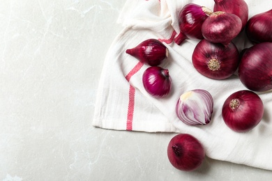Photo of Napkin with fresh red onion bulbs and space for text on white marble table, flat lay