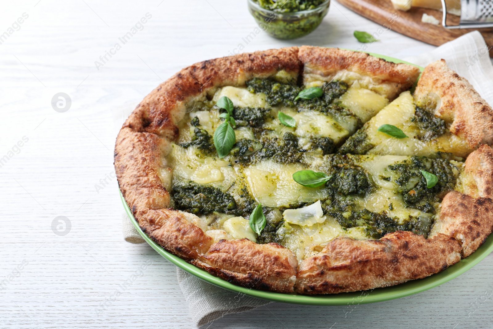 Photo of Delicious pizza with pesto, cheese and basil on white wooden table