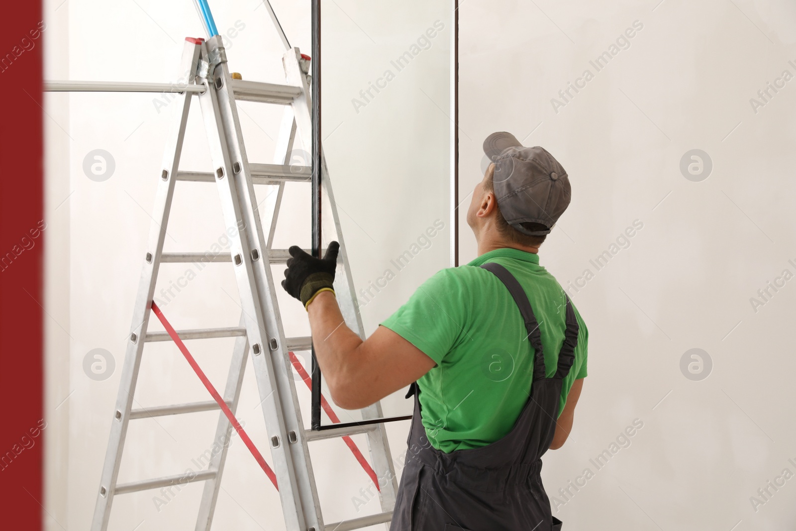 Photo of Worker holding double glazing near ladder indoors. Window installation