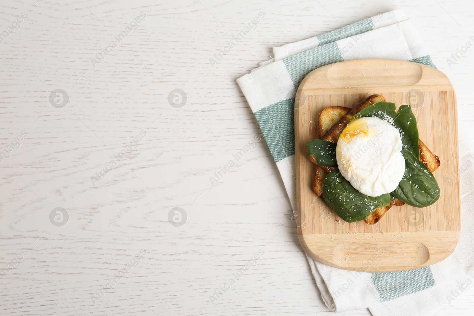 Photo of Delicious poached egg with toasted bread and spinach served on white wooden table, flat lay. Space for text
