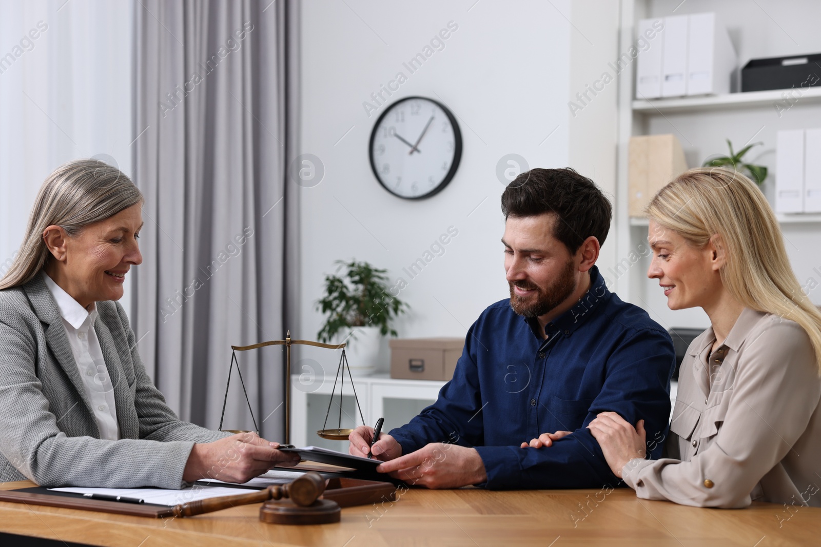Photo of Happy couple signing document in lawyer's office