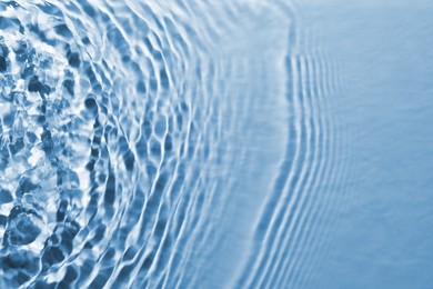 Image of Rippled surface of clear water on light blue background, closeup