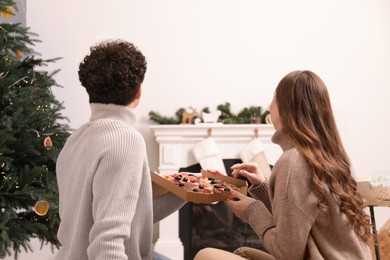 Couple with pizza watching movie via video projector at home, back view