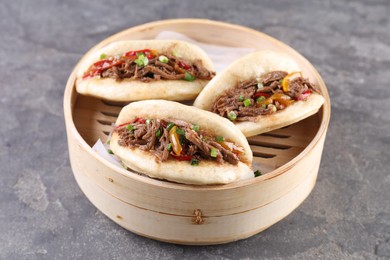 Delicious gua bao in bamboo steamer on grey table