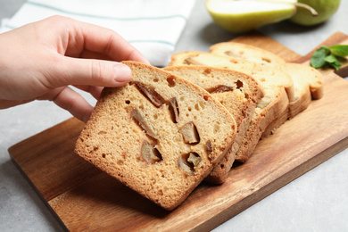 Woman with slice of pear bread at light grey table, closeup. Homemade cake