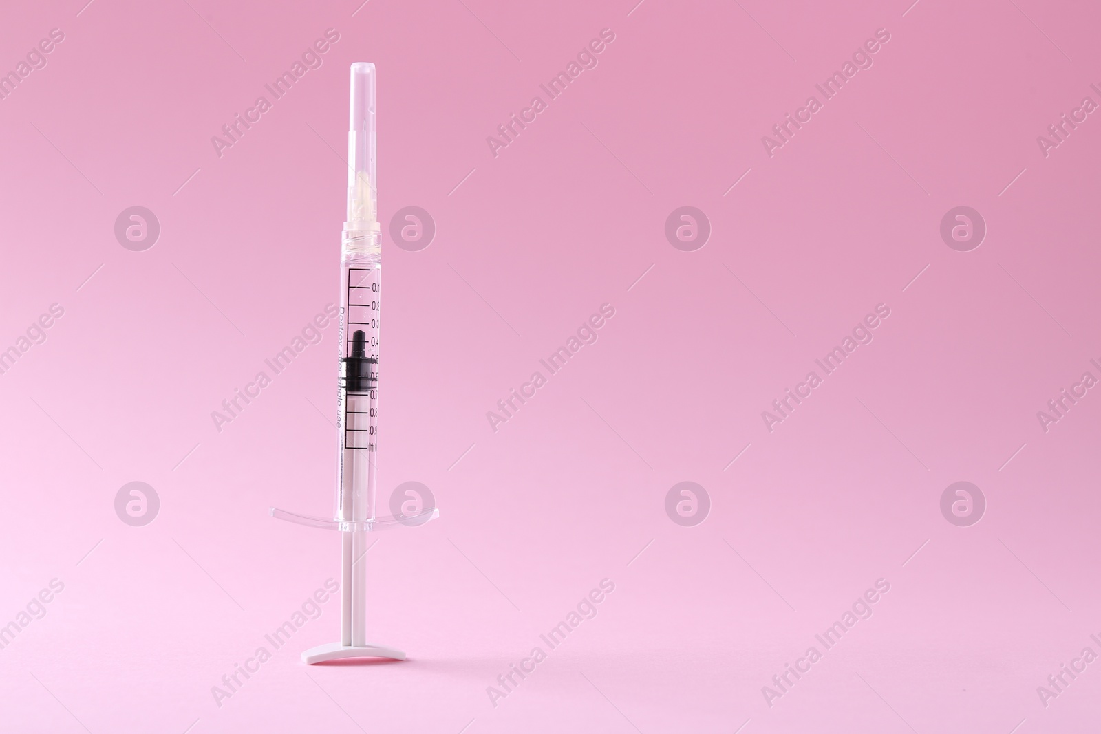 Photo of Cosmetology. Medical syringe on pink background, space for text