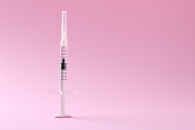 Photo of Cosmetology. Medical syringe on pink background, space for text