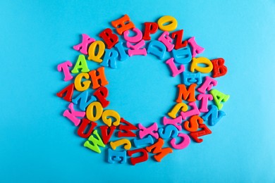 Photo of Frame of colorful magnetic letters on light blue background, flat lay. Space for text