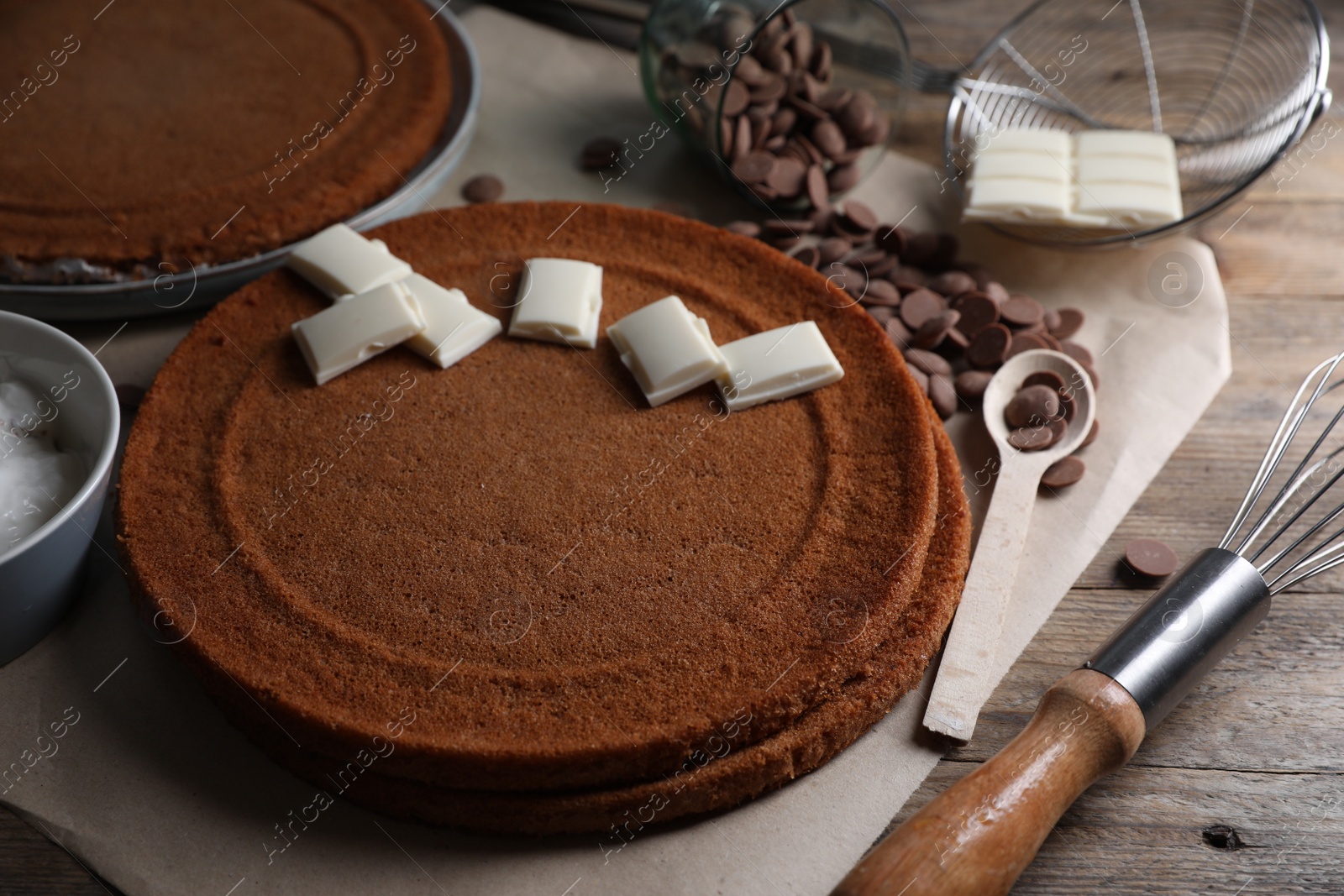 Photo of Delicious homemade sponge cake and different kinds of chocolate on wooden table, closeup