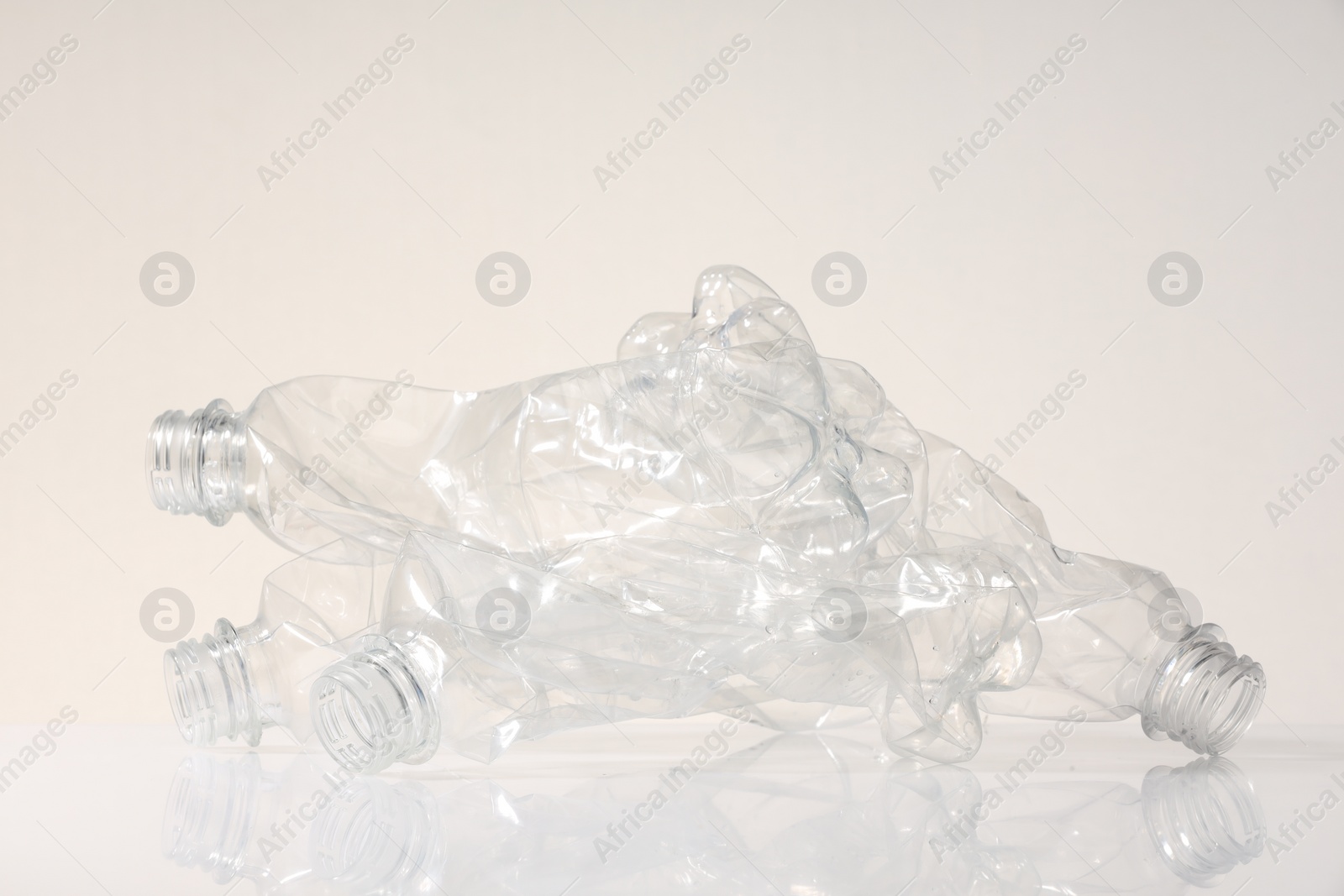 Photo of Crumpled disposable plastic bottles on white background