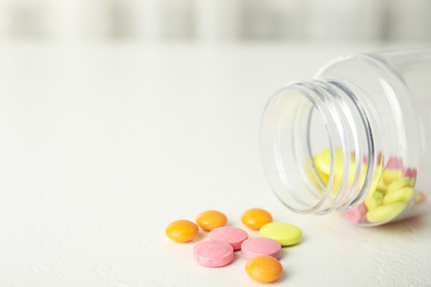 Bottle with vitamin pills on white table, closeup. Space for text