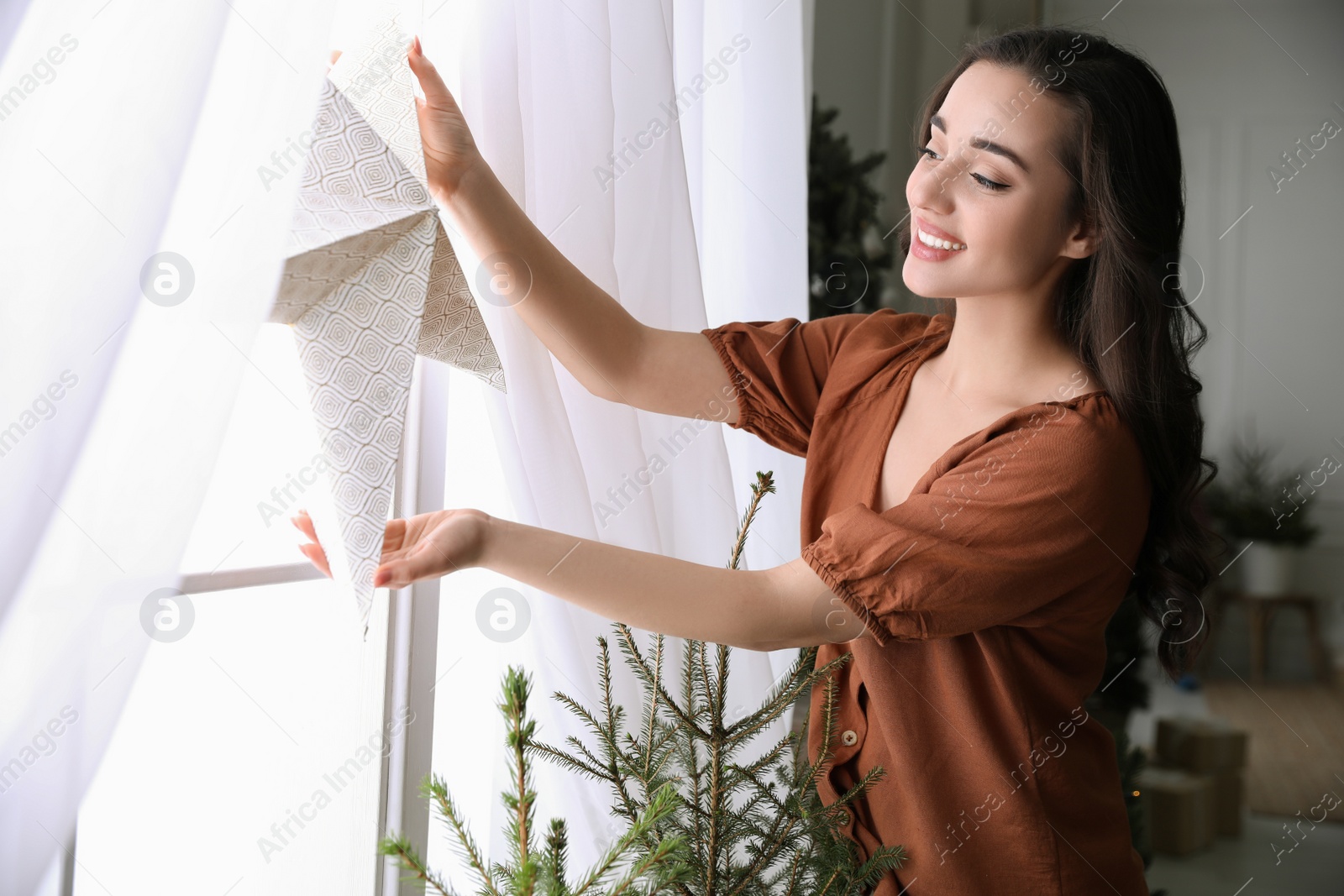 Photo of Woman putting decorative star on window at home