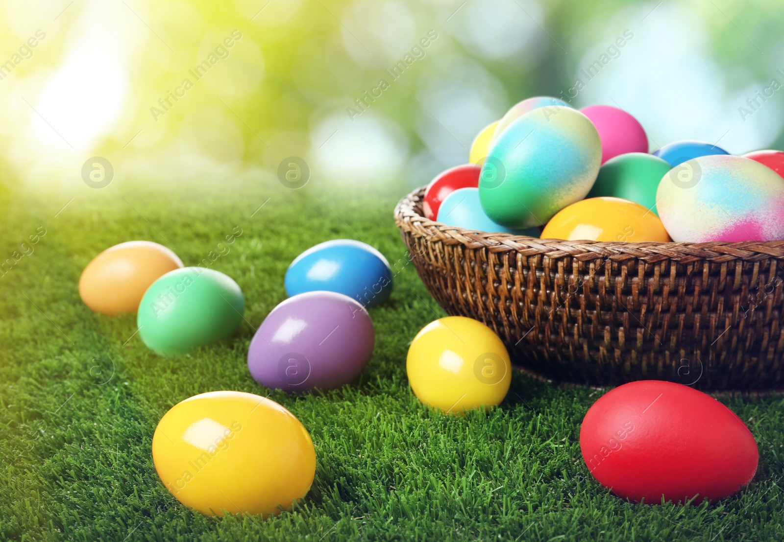 Image of Wicker basket with bright painted Easter eggs on green grass