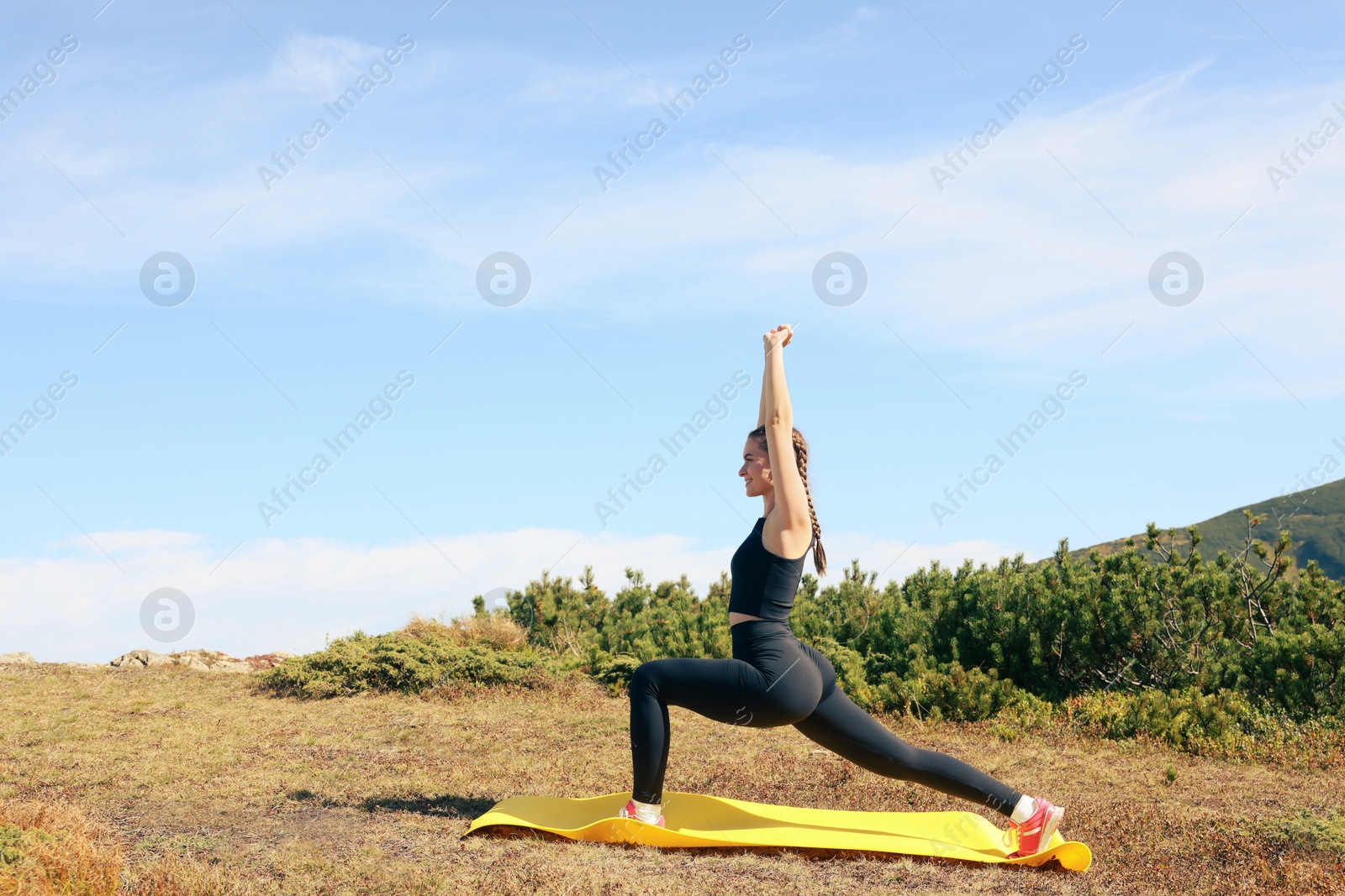 Photo of Beautiful young woman stretching in mountains on summer morning