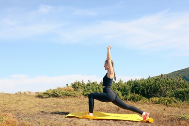 Photo of Beautiful young woman stretching in mountains on summer morning