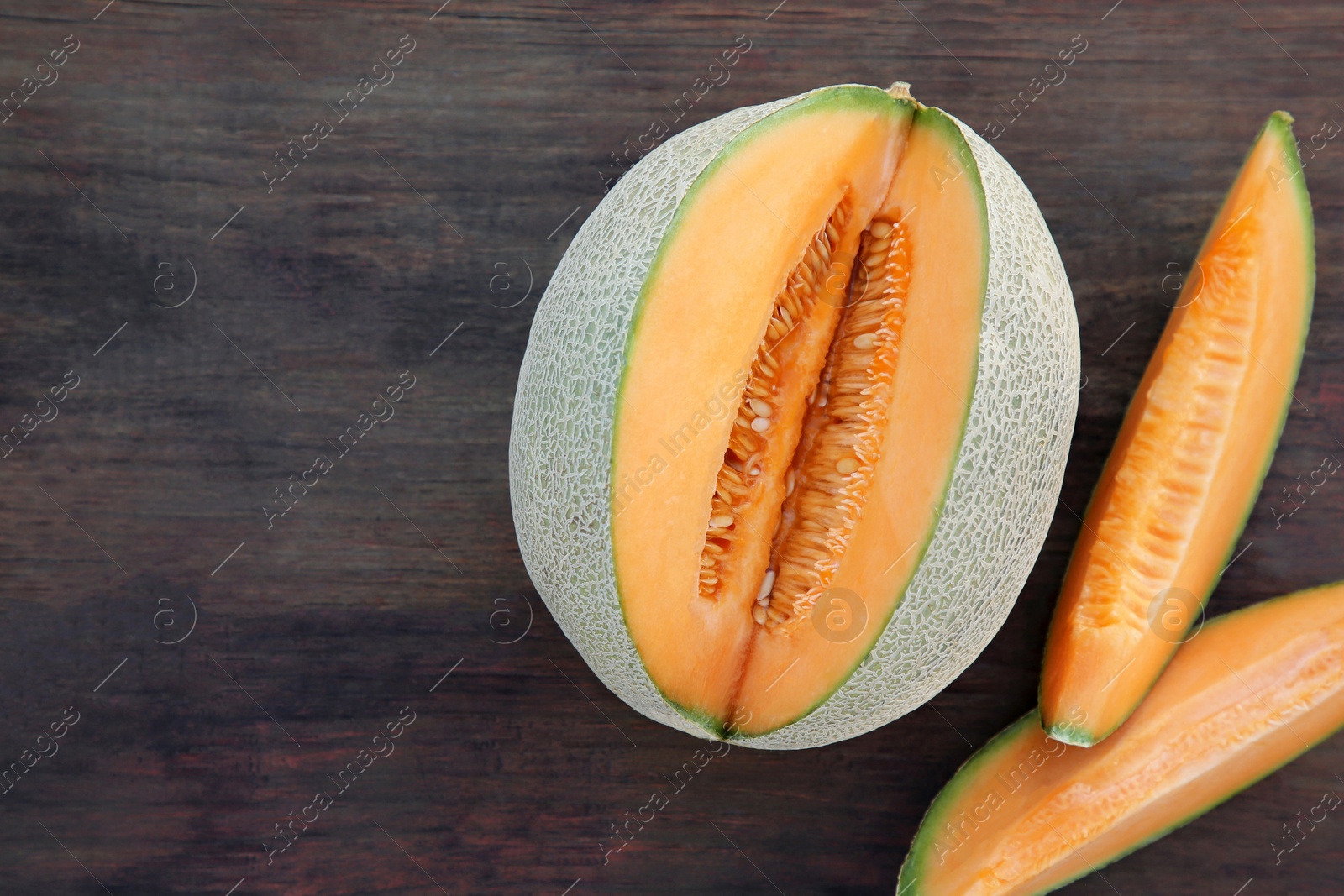 Photo of Cut delicious ripe melon on wooden table, flat lay. Space for text