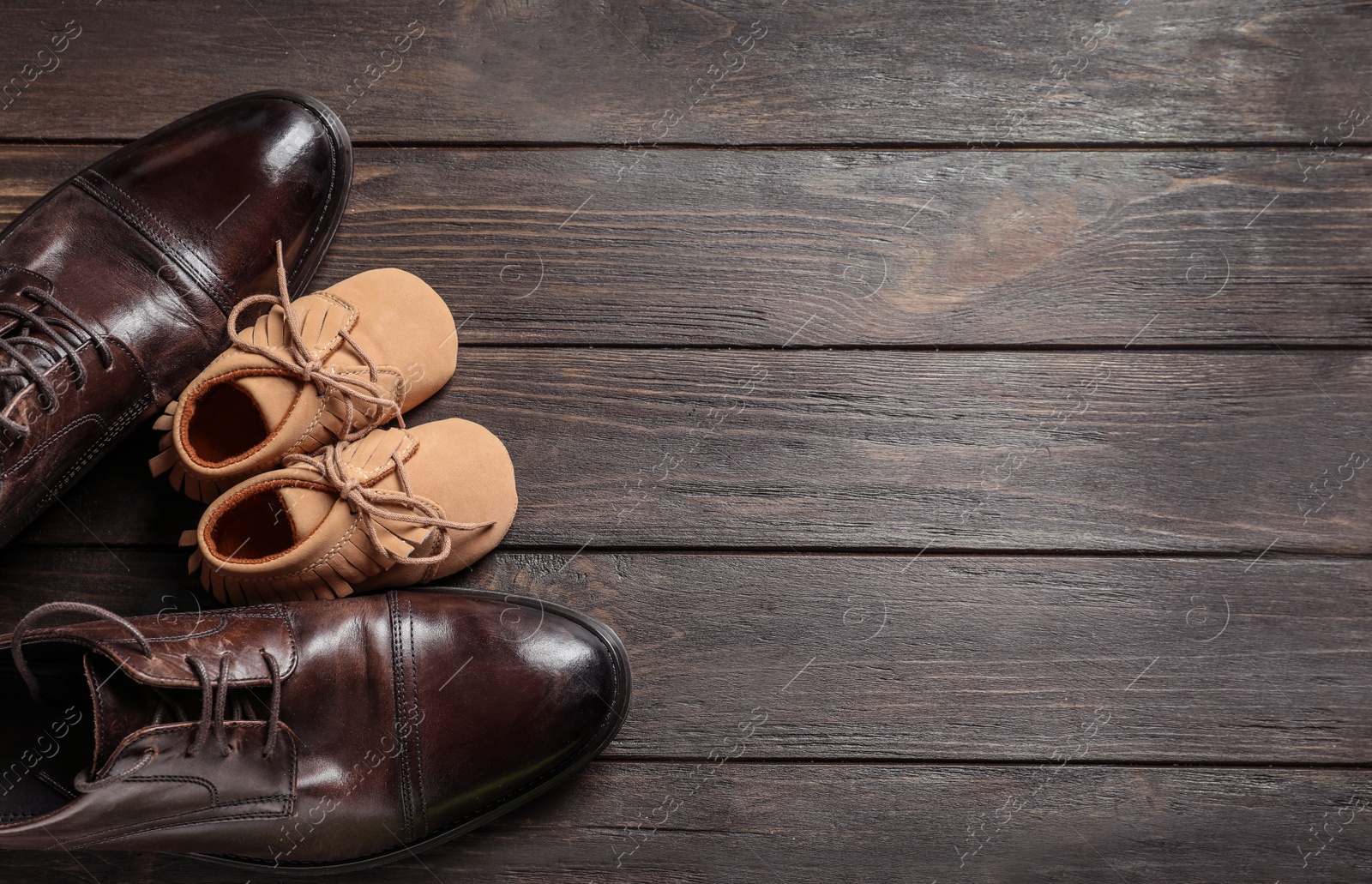 Photo of Flat lay composition with big and small shoes on wooden background. Father's day celebration