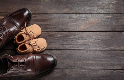 Photo of Flat lay composition with big and small shoes on wooden background. Father's day celebration