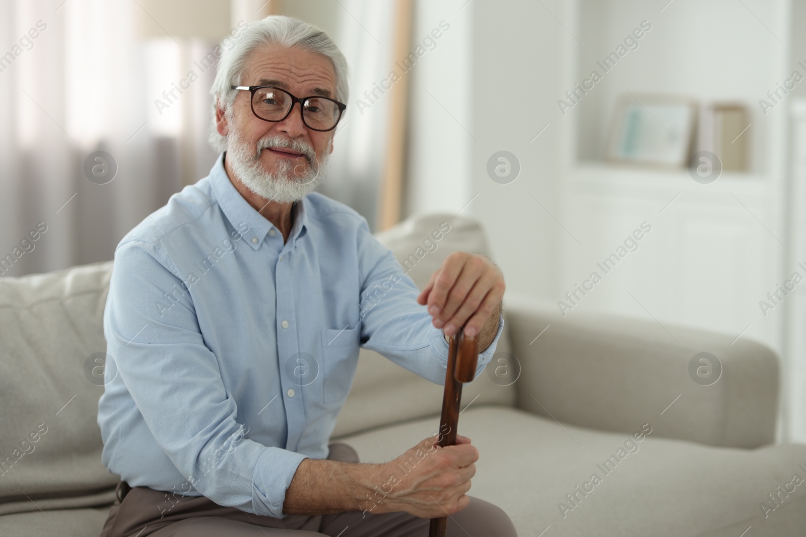 Photo of Portrait of grandpa with glasses and walking cane on sofa indoors