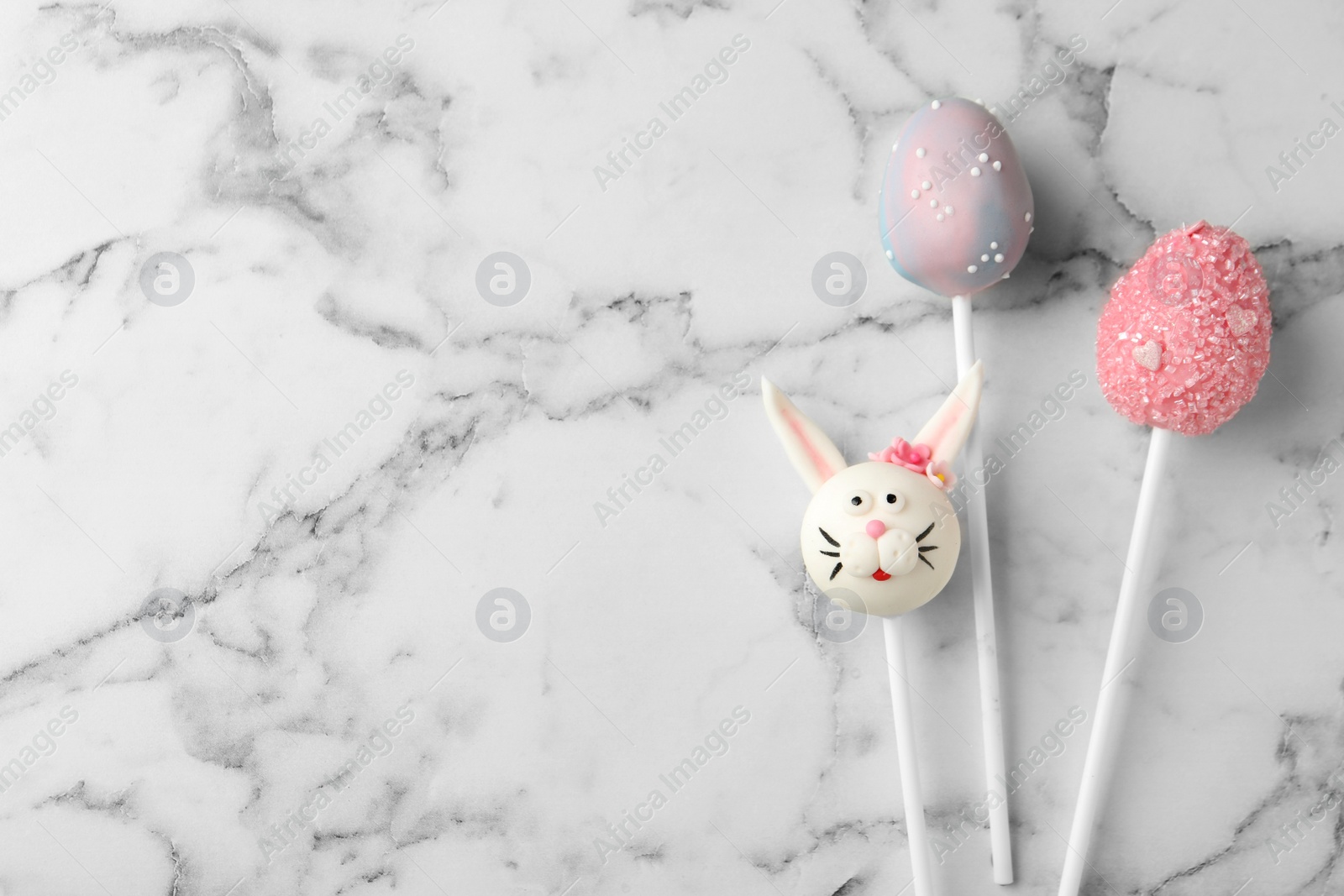 Photo of Delicious sweet cake pops and space for text on white marble table, flat lay. Easter celebration