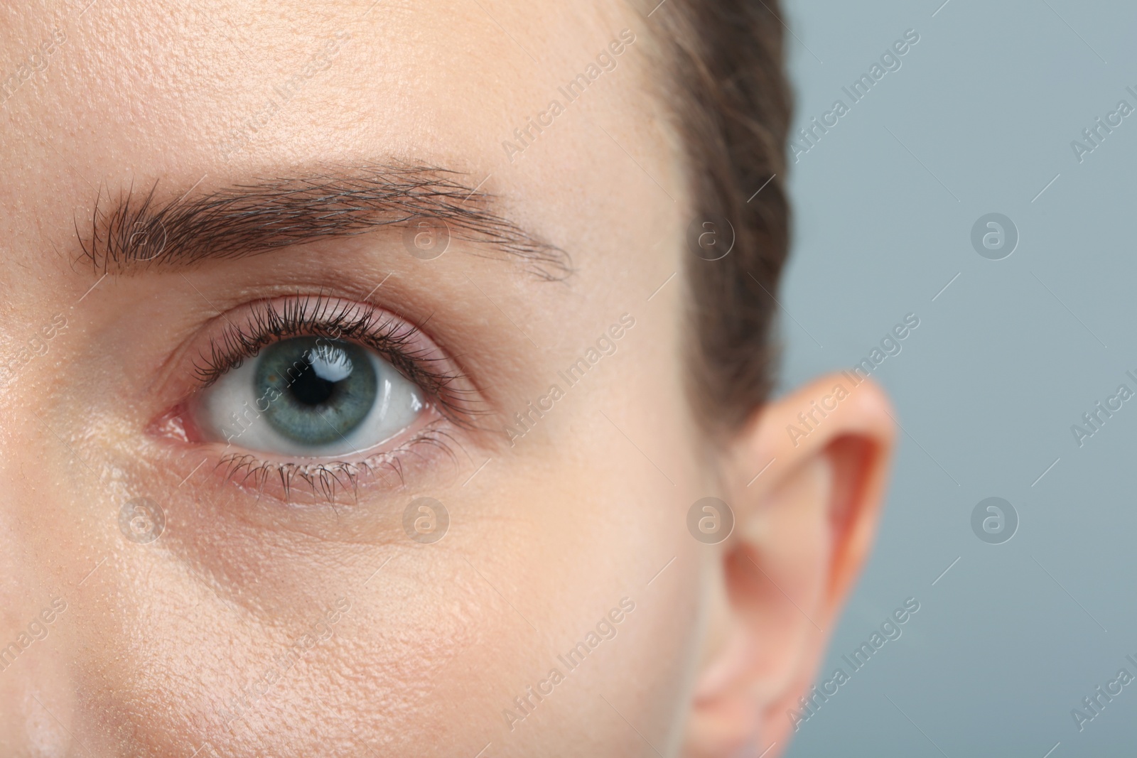 Photo of Woman with beautiful natural eyelashes on grey background, closeup