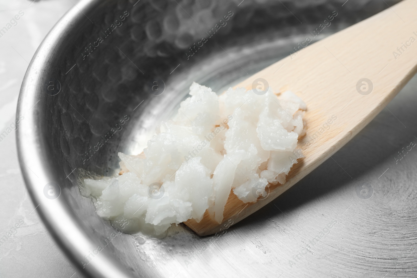 Photo of Frying pan with coconut oil and wooden spatula, closeup. Healthy cooking