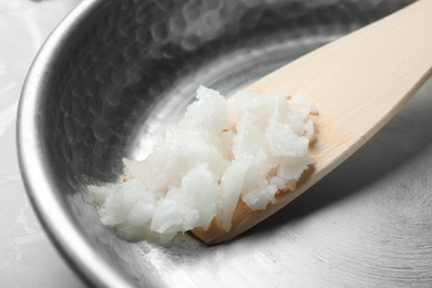 Frying pan with coconut oil and wooden spatula, closeup. Healthy cooking