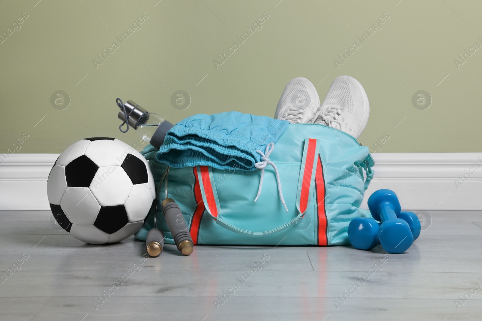 Photo of Bag with different sports equipment on wooden floor indoors