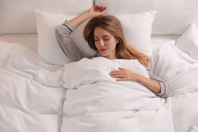Photo of Woman under warm white blanket sleeping in bed indoors, above view