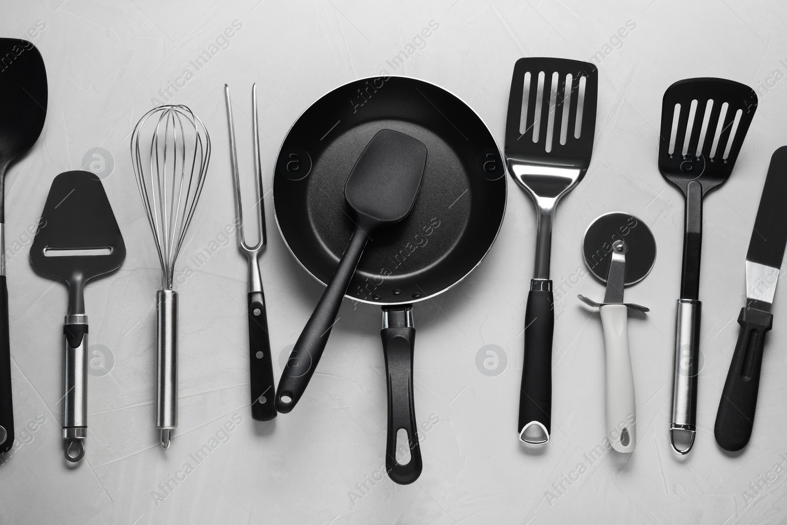 Photo of Different spatulas and other kitchen utensils on grey background, flat lay