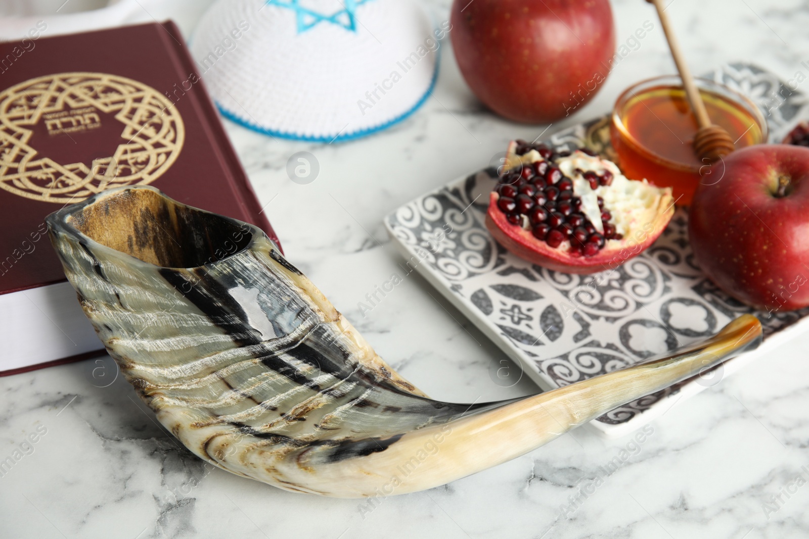 Photo of Composition with Rosh Hashanah holiday symbols on white marble table, closeup