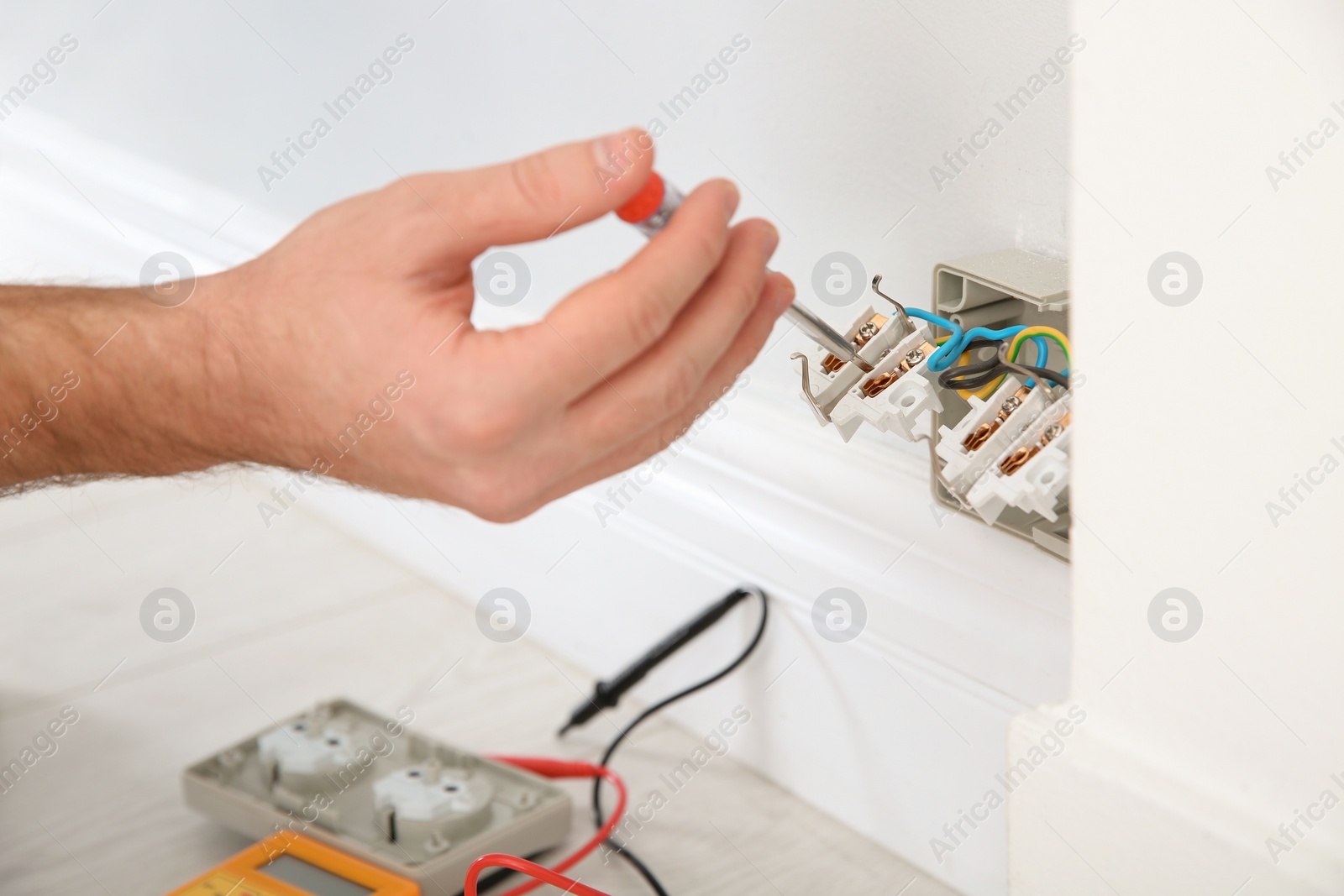 Photo of Electrician with neon-lamp tester checking voltage indoors, closeup