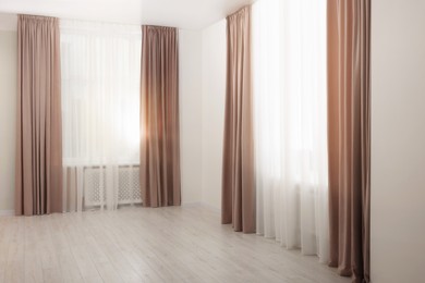Photo of Elegant window curtains and white tulle indoors. Interior design