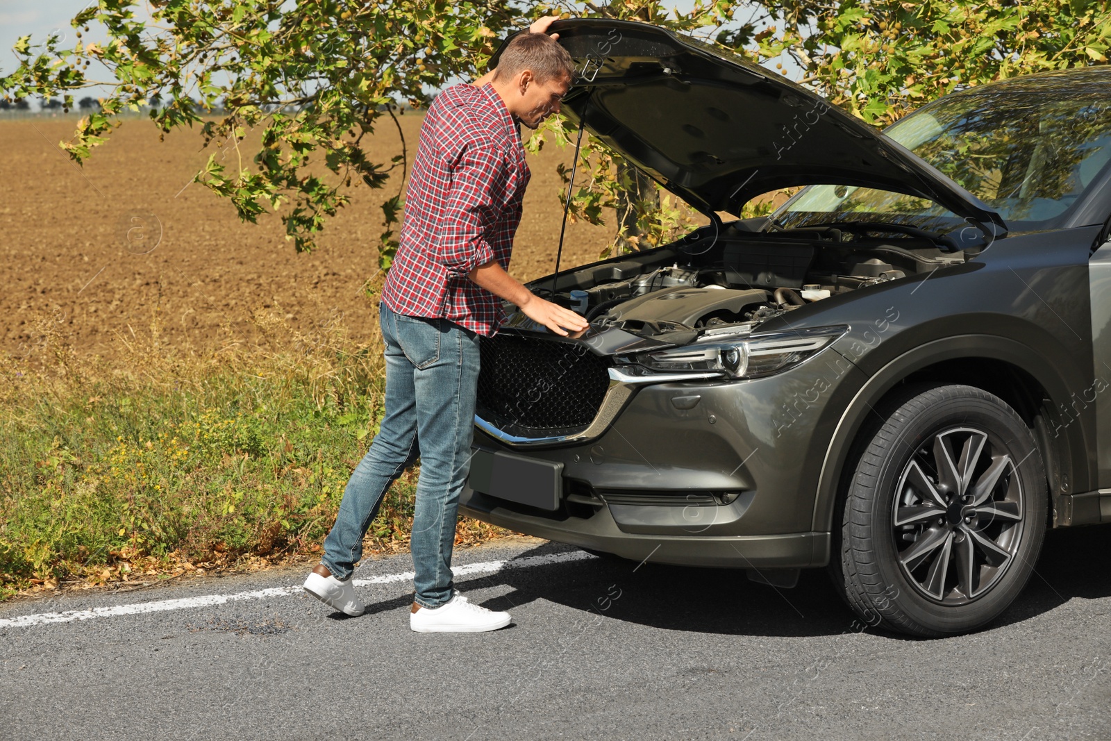 Photo of Man near broken car on road. Auto insurance