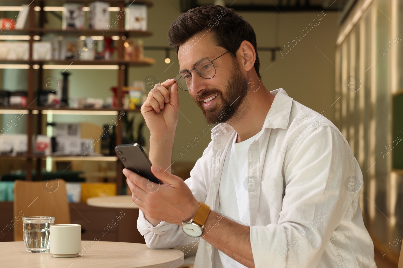 Photo of Handsome man using smartphone at table in cafe