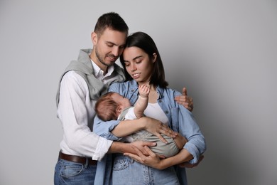 Photo of Happy family. Couple with their cute baby on grey background