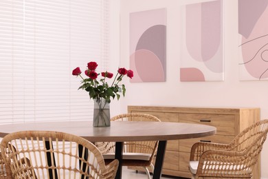 Chairs and table with vase of red rose flowers in dining room. Stylish interior