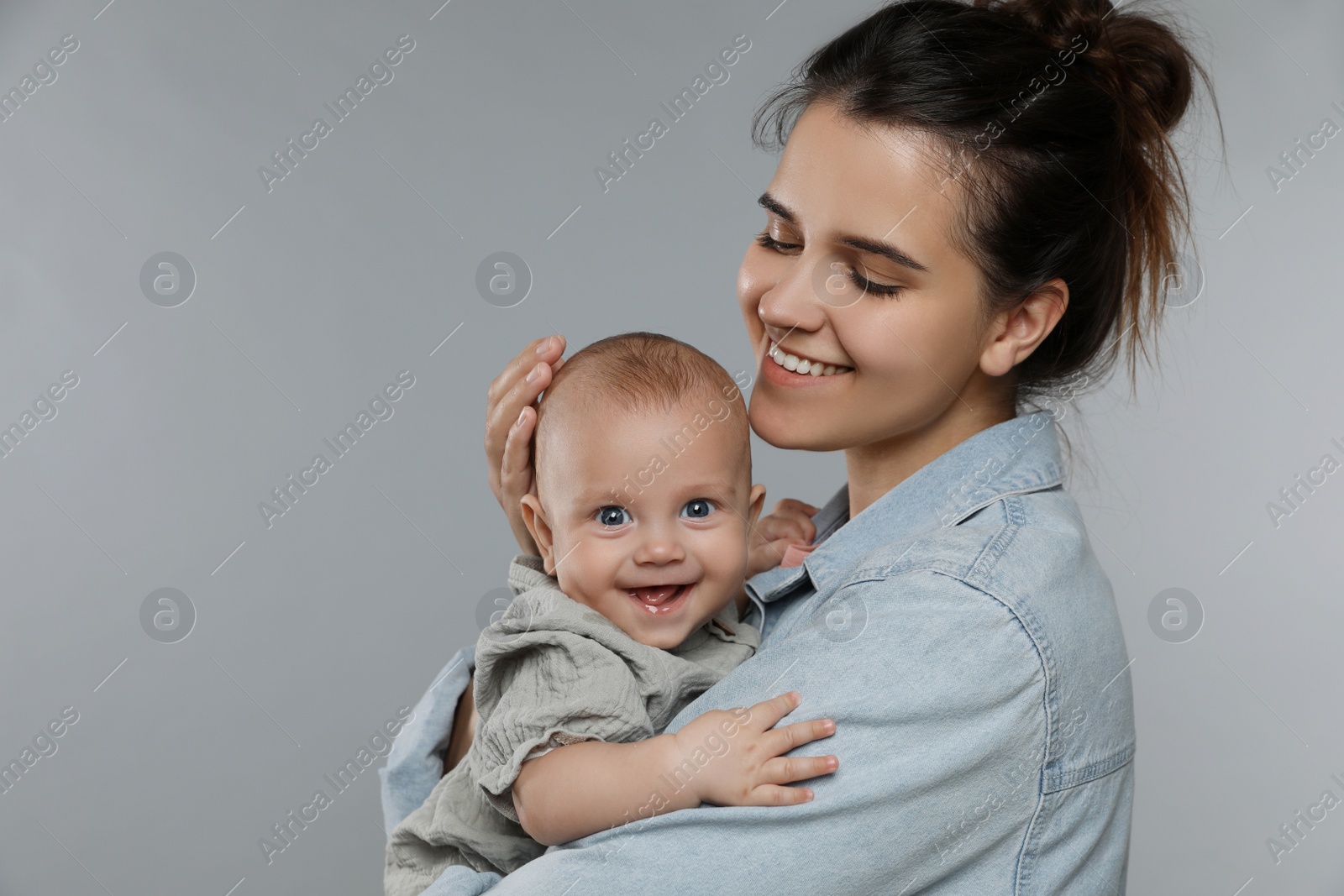 Photo of Beautiful mother with her cute baby on grey background. Space for text